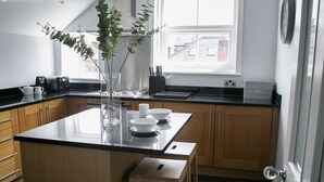 Et moderne køkken med træskabe, en sort bordplade og en central ø med barstole.
