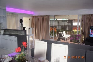 A modern living room with a sofa, dining table, and kitchen area.
