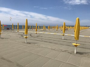 Ein Strand mit Reihen gelber Sonnenschirme und einigen roten.