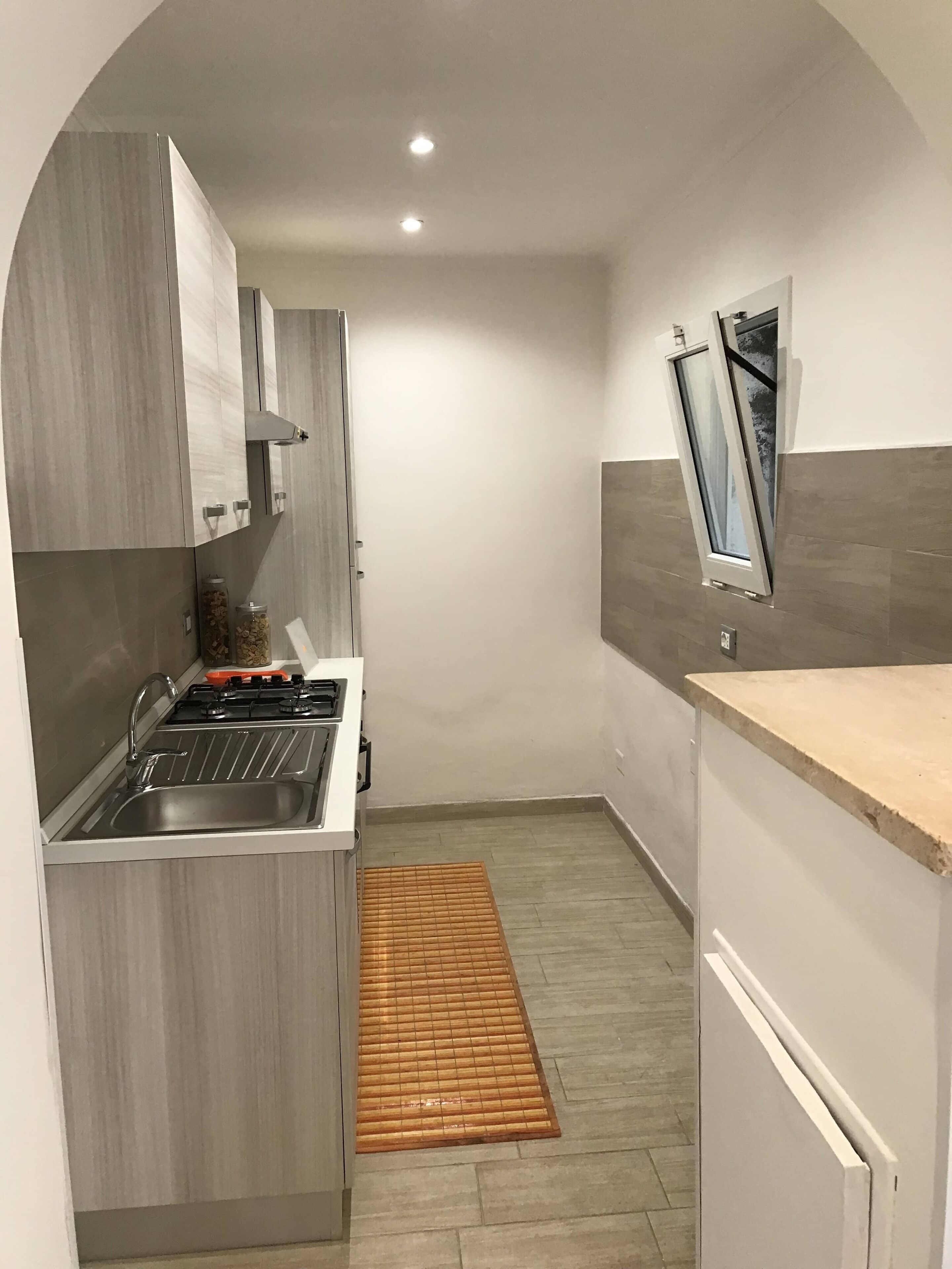 A compact kitchen with a built-in gas stove, a stainless steel sink, and a small window.