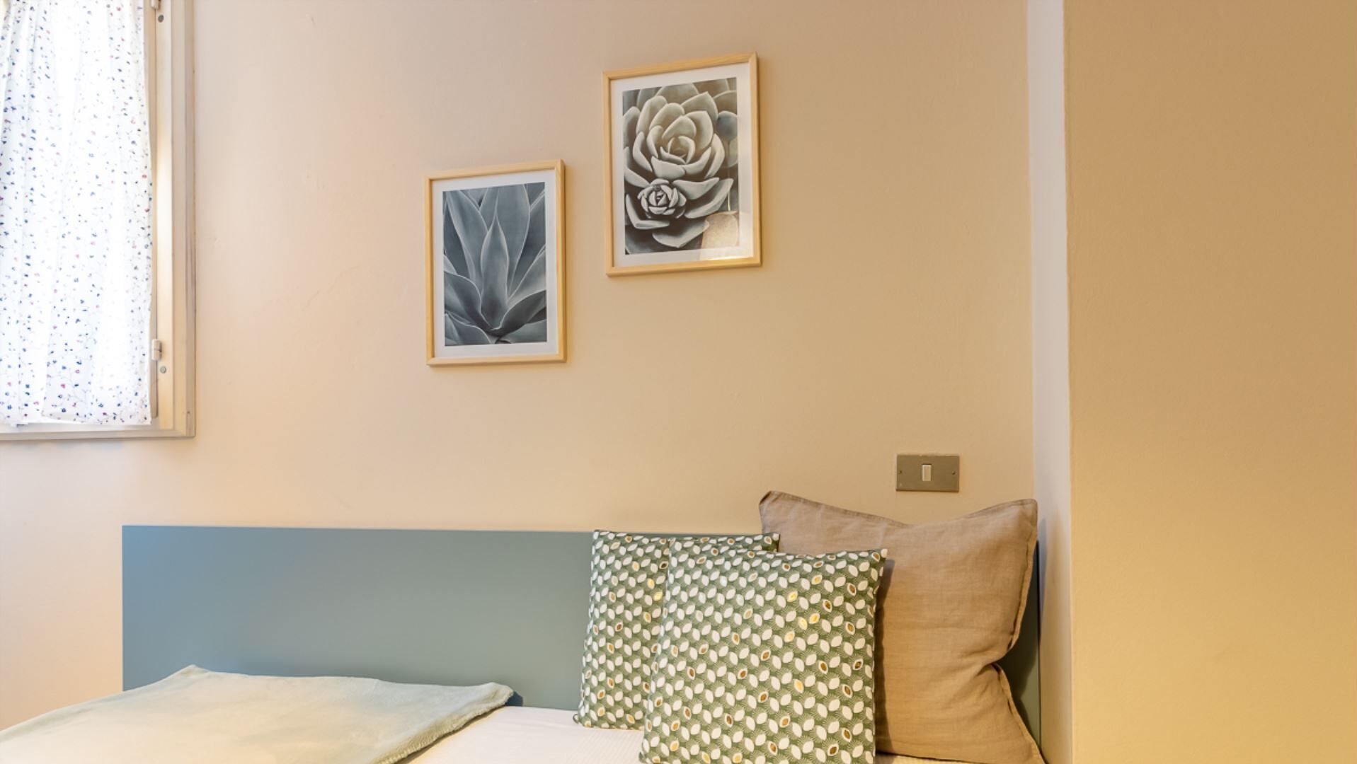 Ein Schlafzimmer mit einem Bett, zwei Kissen und zwei gerahmten Kunstwerken an der Wand.