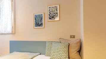 Ein Schlafzimmer mit einem Bett, zwei Kissen und zwei gerahmten Kunstwerken an der Wand.