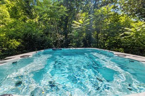 A hot tub surrounded by lush greenery. - Secluded 3 King Suite Gatlinburg Cabin | Swim Spa+Hot Tub, Games & Flat Parking (Gatlinburg)