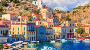 A coastal town with colorful buildings, a marina with boats, and rocky hills in the background. - SeaMe House I (Symi)