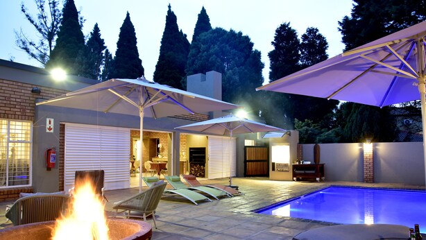 Un jardin avec une piscine, un espace salon extérieur et un foyer.