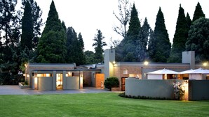 Une maison moderne dotée d’une pelouse bien entretenue, d’un garage et d’un espace extérieur couvert agrémenté de parasols.