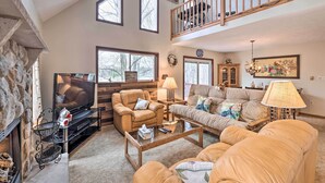 A spacious living room with a fireplace, a television, leather sofas, and a wooden coffee table. - Walk to Beach: Lakefront Pocono Escape w/ Fire Pit (Pocono Lake)