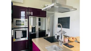 Eine moderne Küche mit Edelstahlgeräten, einem eingebauten Backofen, einer Mikrowelle und einem großen Spülbecken mit einem zeitgemäßen Wasserhahn.