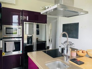 A modern kitchen with stainless steel appliances, a built-in oven, a microwave, and a large sink with a contemporary faucet.