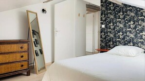 Ein Schlafzimmer mit Bett, Schminktisch, Spiegel und einer Tür zu einem anderen Raum.