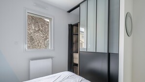 A bedroom with a bed, a window with a view of trees, a radiator, and a sliding door leading to a closet. - House for 6 people in Saint Michel Chef Chef (Saint-Michel-Chef-Chef)