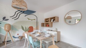 A dining area with a table set for four, chairs, a wall-mounted shelf, and a hanging light fixture. - House for 6 people in Saint Michel Chef Chef (Saint-Michel-Chef-Chef)