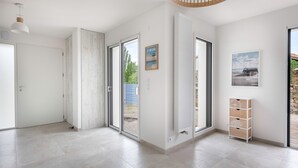 A spacious room with a large sliding glass door leading to an outdoor area, a white radiator, and a small wooden cabinet with drawers. - House for 6 people in Saint Michel Chef Chef (Saint-Michel-Chef-Chef)