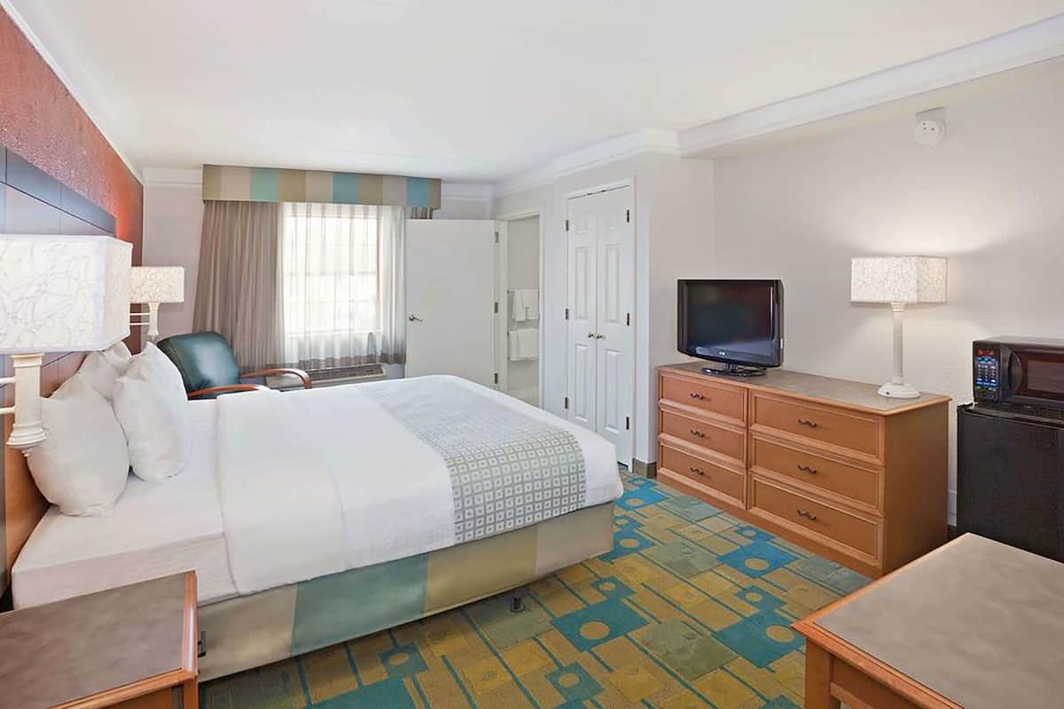Een hotelkamer met een bed, een televisie, een bureau en een dressoir.