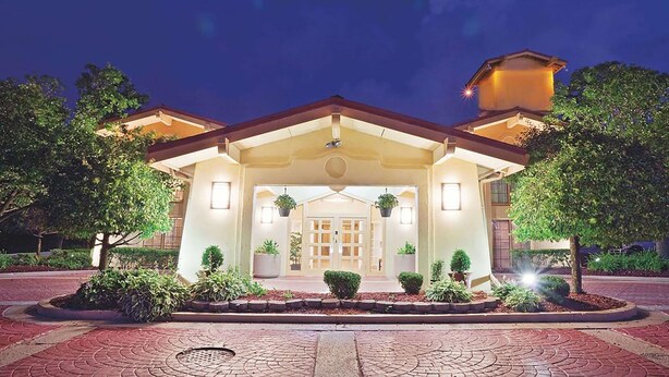 A hotel entrance with a covered walkway, potted plants, and a brick pathway.