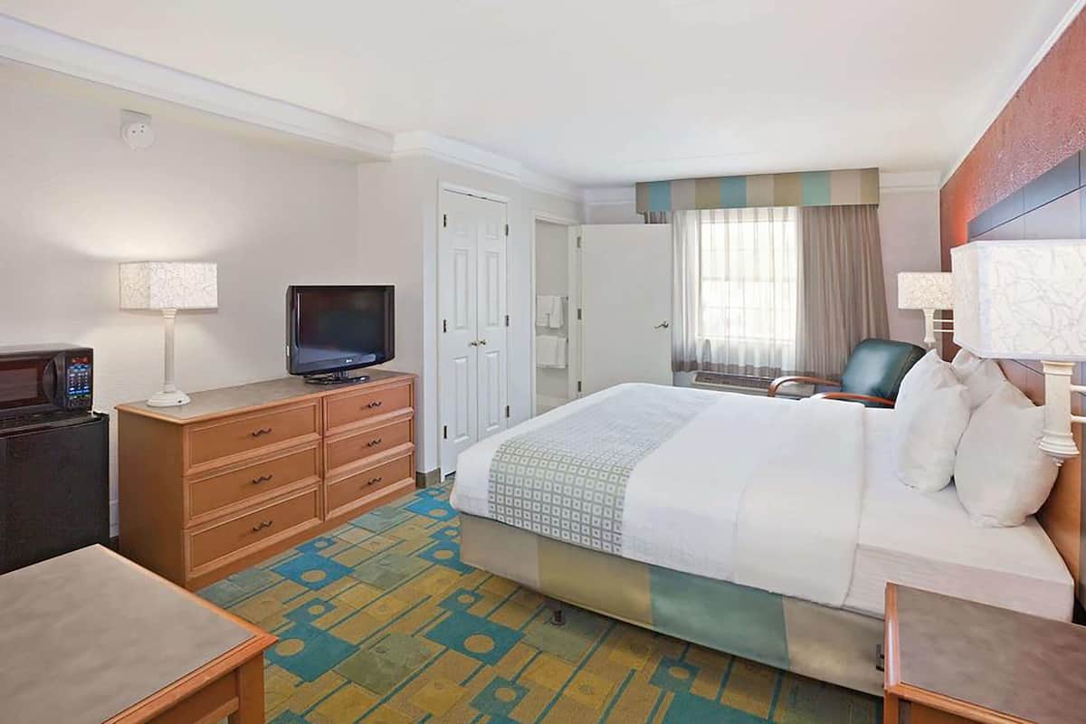 Een hotelkamer met een bed, een televisie, een bureau, een stoel en een lamp.