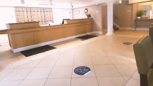 A reception area with a wooden counter, a black mat, and a manhole cover on the floor.