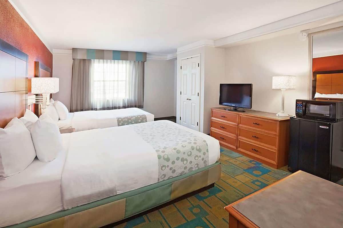Een hotelkamer met twee bedden, een televisie, een magnetron en een bureau.