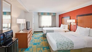 A hotel room with two beds, a TV, a microwave, and a minibar.