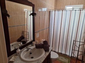 Een badkamer met een wastafel, spiegel en douchegordijn met strepen.