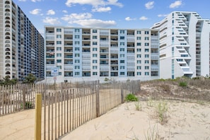 A multi-story hotel with a modern design, featuring balconies and a beach view.