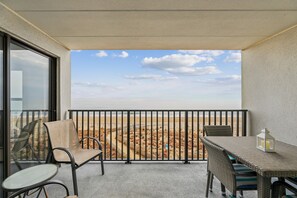 Un balcon donnant sur la plage, aménagé avec une table et des chaises.