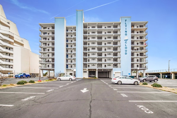 A multi-story residential building with a central entrance and parking lot.