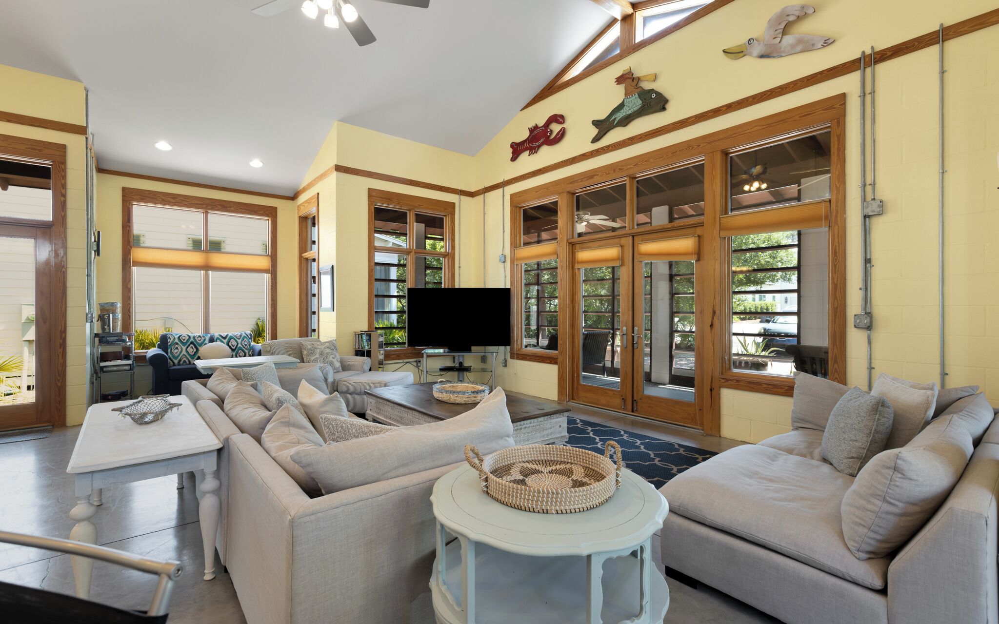 A spacious living room with a sectional sofa, a television, and large windows.