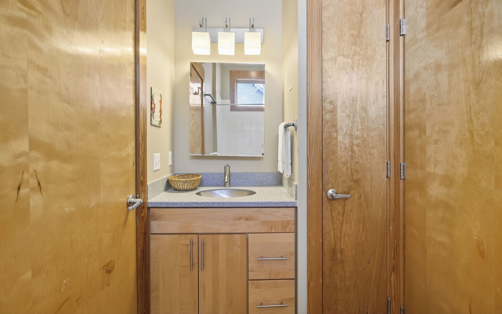 A wooden bathroom with a sink, mirror, and cabinets.