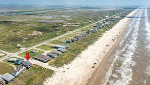 An aerial view of a coastal area with a long row of buildings along the beach, a road, and a large body of water. - Starfish Beach Gem - Right ON Beach & So Lovely! (Surfside Beach)