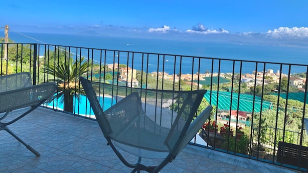 Uma varanda com vista para o mar, uma piscina e uma cadeira.