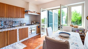 Uma cozinha com armários de madeira, painel de azulejos e uma área de jantar com mesa e cadeiras.