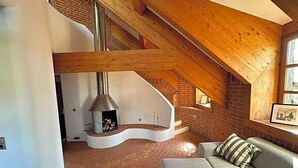 A loft-style room with a curved staircase, a fireplace, and a sofa. - Aquaquell Bad Pilzweg Hotel & Spa (Fuerstenzell)
