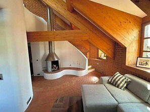 A loft-style room with a curved staircase, a fireplace, and a sofa. - Aquaquell Bad Pilzweg Hotel & Spa (Fuerstenzell)