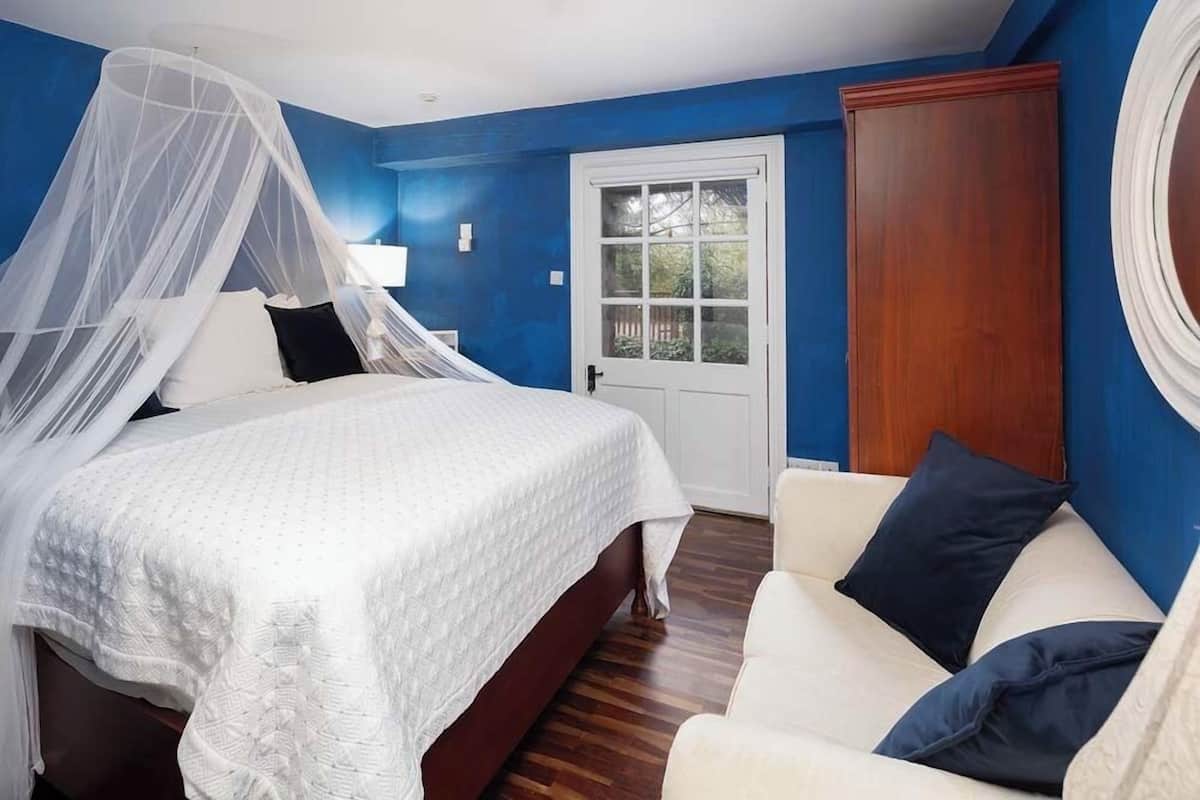 Un dormitorio con una cama, una mesita de noche, una silla, una ventana y una puerta.