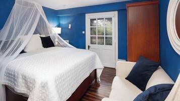 A bedroom with a bed, a nightstand, a chair, a window, and a door.