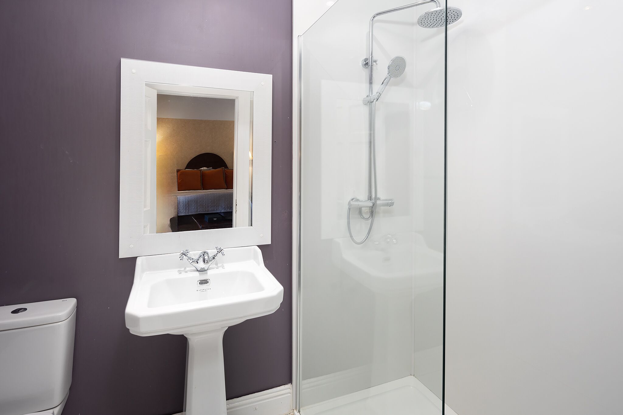 A bathroom with a white sink, a mirror, and a glass-enclosed shower.