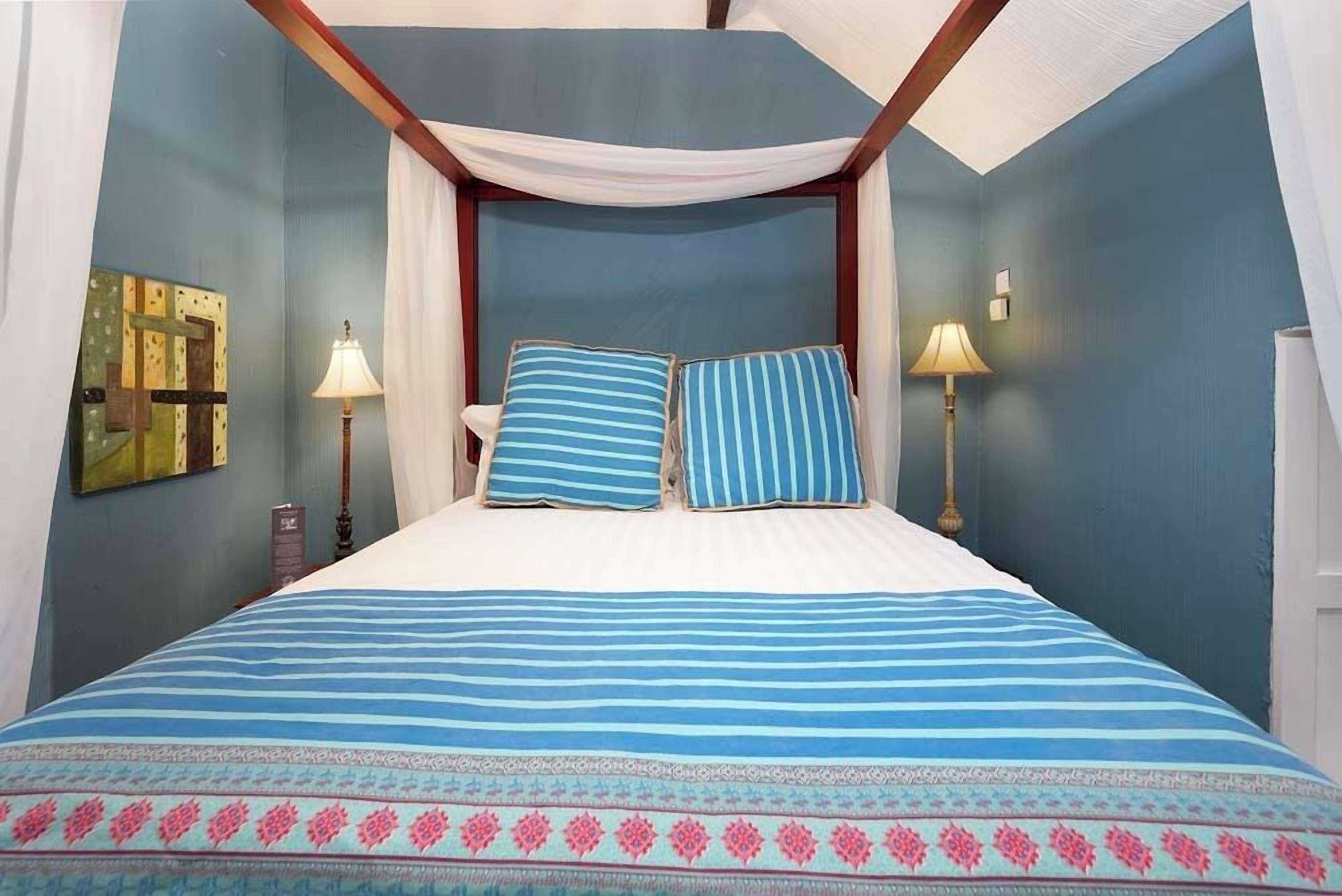 Un dormitorio con cama con dosel, dos lámparas de noche y un adorno en la pared.