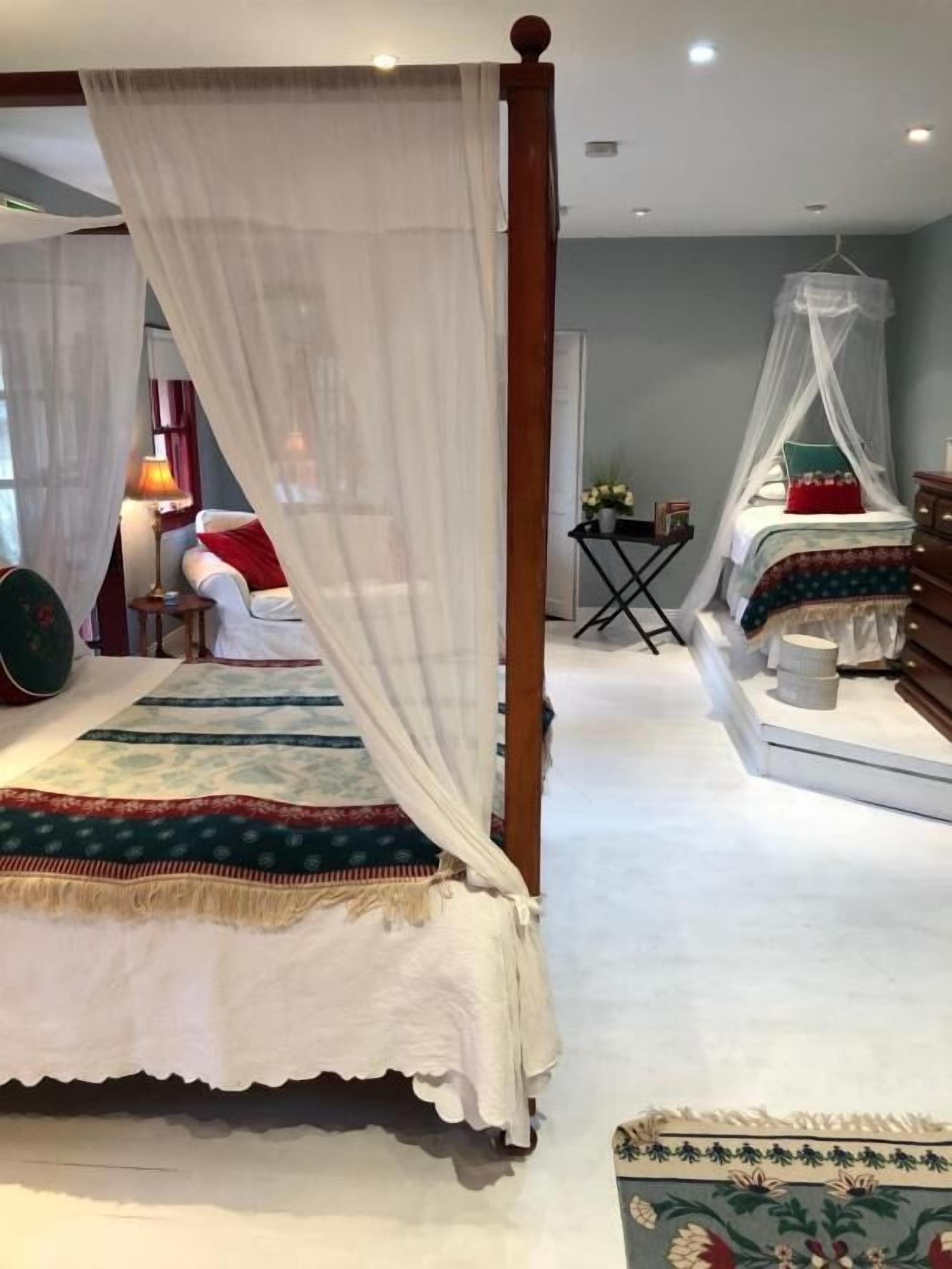 Ein Schlafzimmer mit einem Himmelbett, einem kleinen Tisch mit Lampe und einem Sessel.