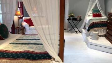 Ein Schlafzimmer mit einem Himmelbett, einem kleinen Tisch mit Lampe und einem Sessel.