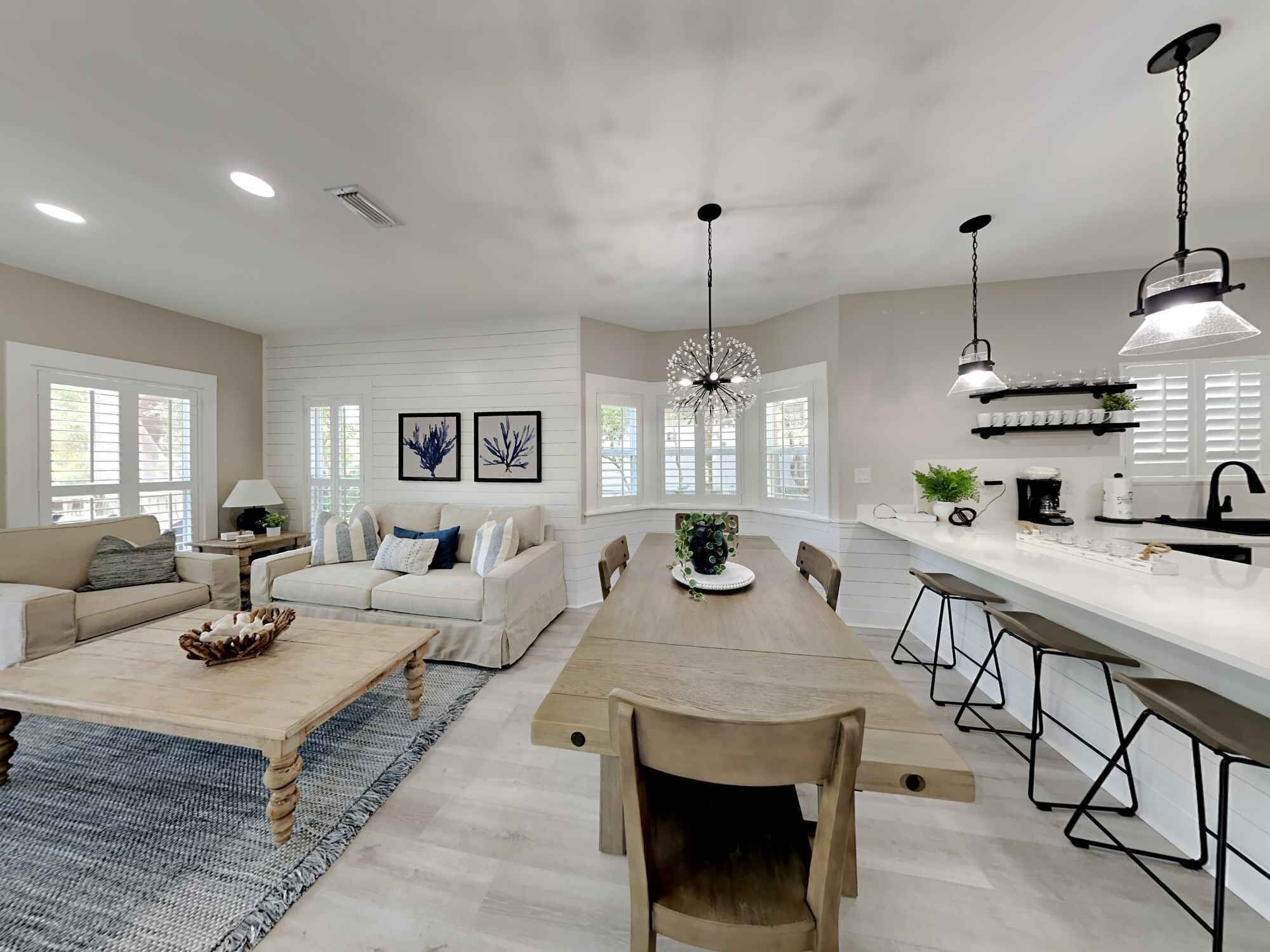 A modern kitchen with a central island, bar stools, and pendant lighting.