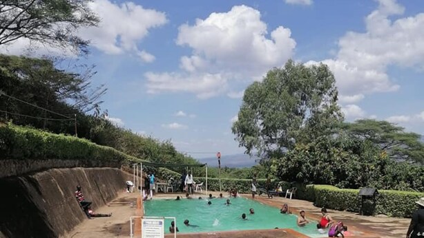 A swimming pool area with a tiled floor, surrounded by trees and a clear sky. - Sego Safari Lodge (Eldoret)