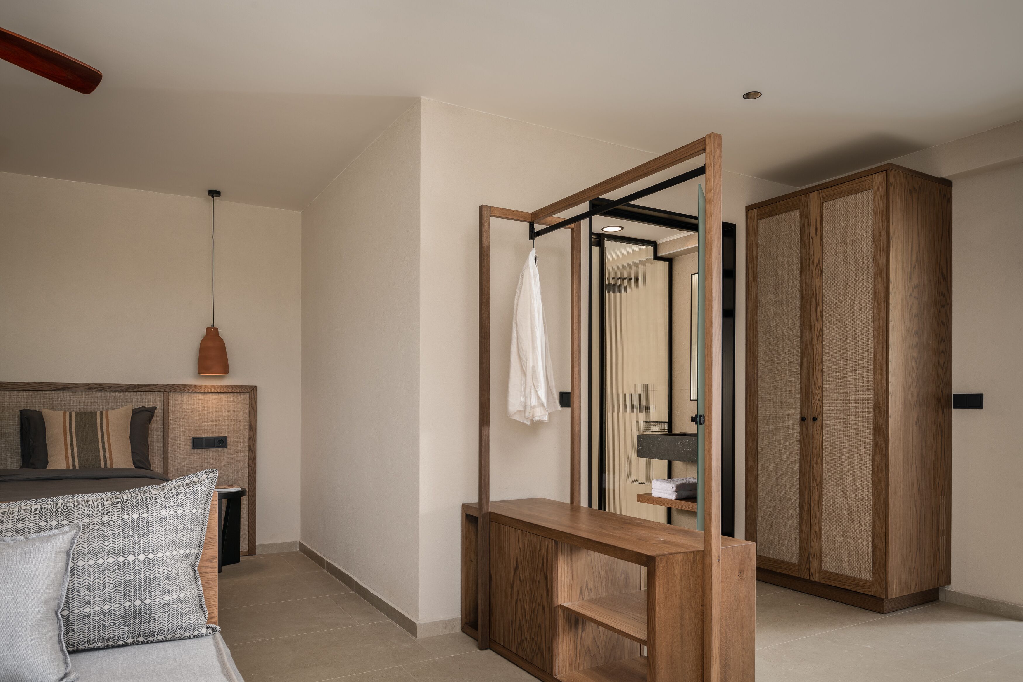 A modern bedroom with a wooden headboard, a bedside table, a mirror, and a wardrobe.