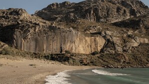 Ein Strand mit einer steinigen Klippe im Hintergrund.