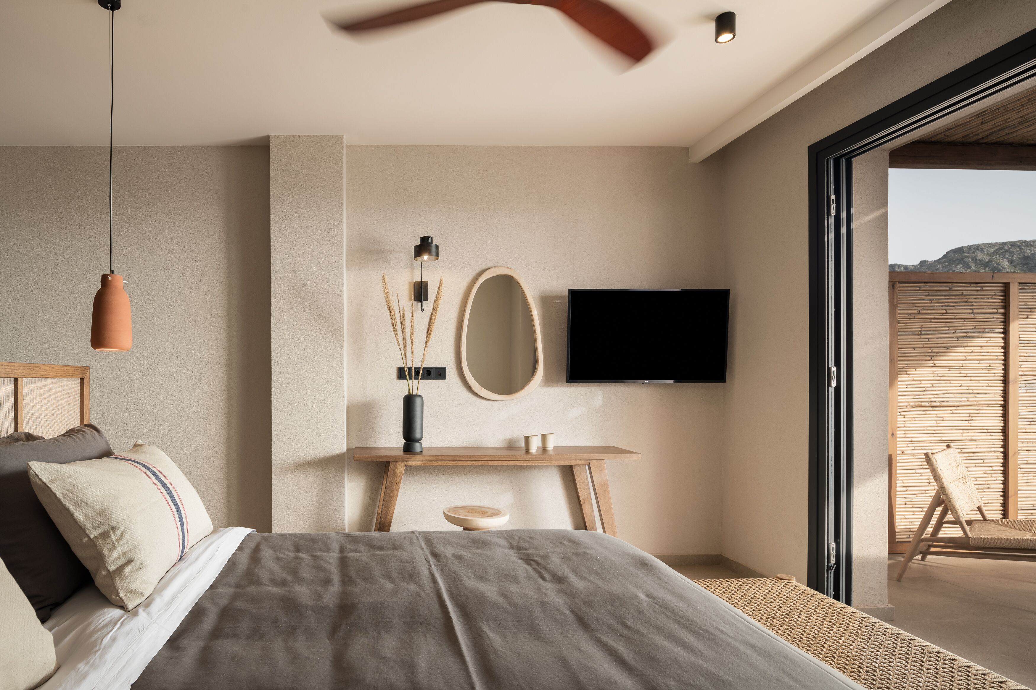 A modern bedroom with a bed, bedside table, mirror, and a TV.