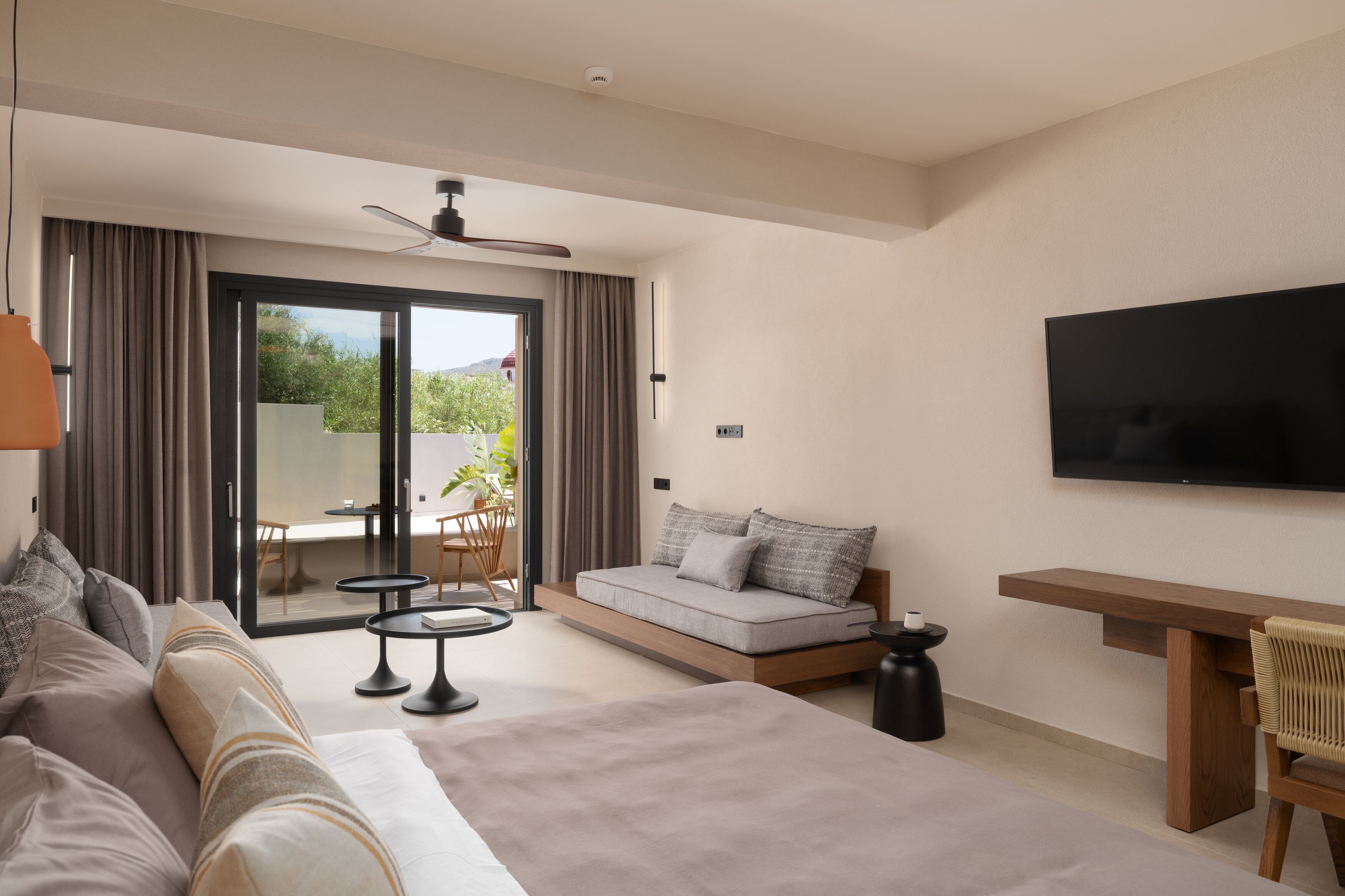 Una habitación de hotel moderna con una cama grande, un sofá, una mesa de comedor y un televisor montado en la pared.