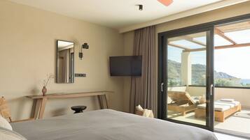 Quarto de hotel moderno com uma cama grande, televisão de tela plana, escrivaninha de madeira e varanda com vista para as montanhas.