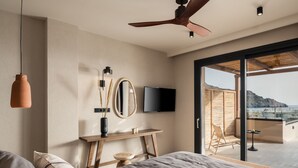 Ein Schlafzimmer mit Bett, Fernseher, Deckenventilator und Blick ins Freie.