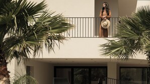 Ein modernes, zweistöckiges Gebäude mit Balkon, Palmen und einem Schild mit der Aufschrift 'KYMANI'.