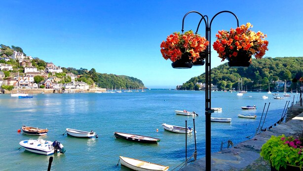 A coastal town with boats docked along the waterfront, a clear blue sky, and houses on a hillside. - Spacious Luxury Retreat with parking & views (Kingswear)